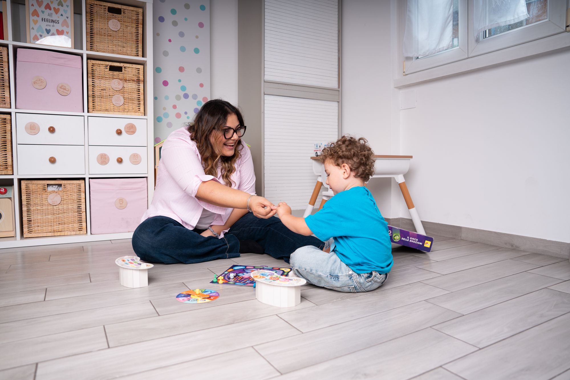 La Dott.ssa Federica Grasso gioca sul pavimento con un bambino nella stanza bambini dello studio